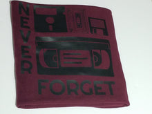Load image into Gallery viewer, Black ink Never Forget design with cassette, VHS, and retro icons on burgundy unisex short sleeve Chozzen Few cotton T-shirt
